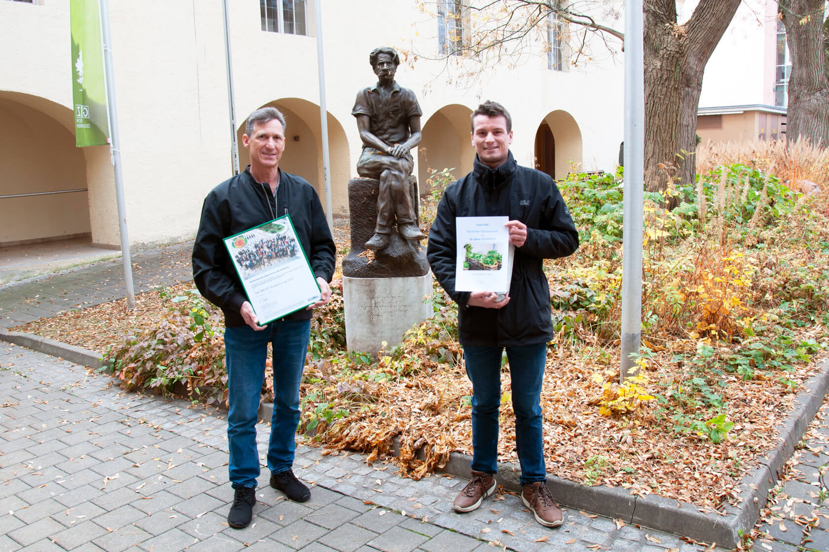 Übergabe der Ökoprofit Auszeichnung an Hans Schlager durch einen Vertreter des Umweltamtes vor der Albert Schweitzer Statue am Gelände der GGZ
