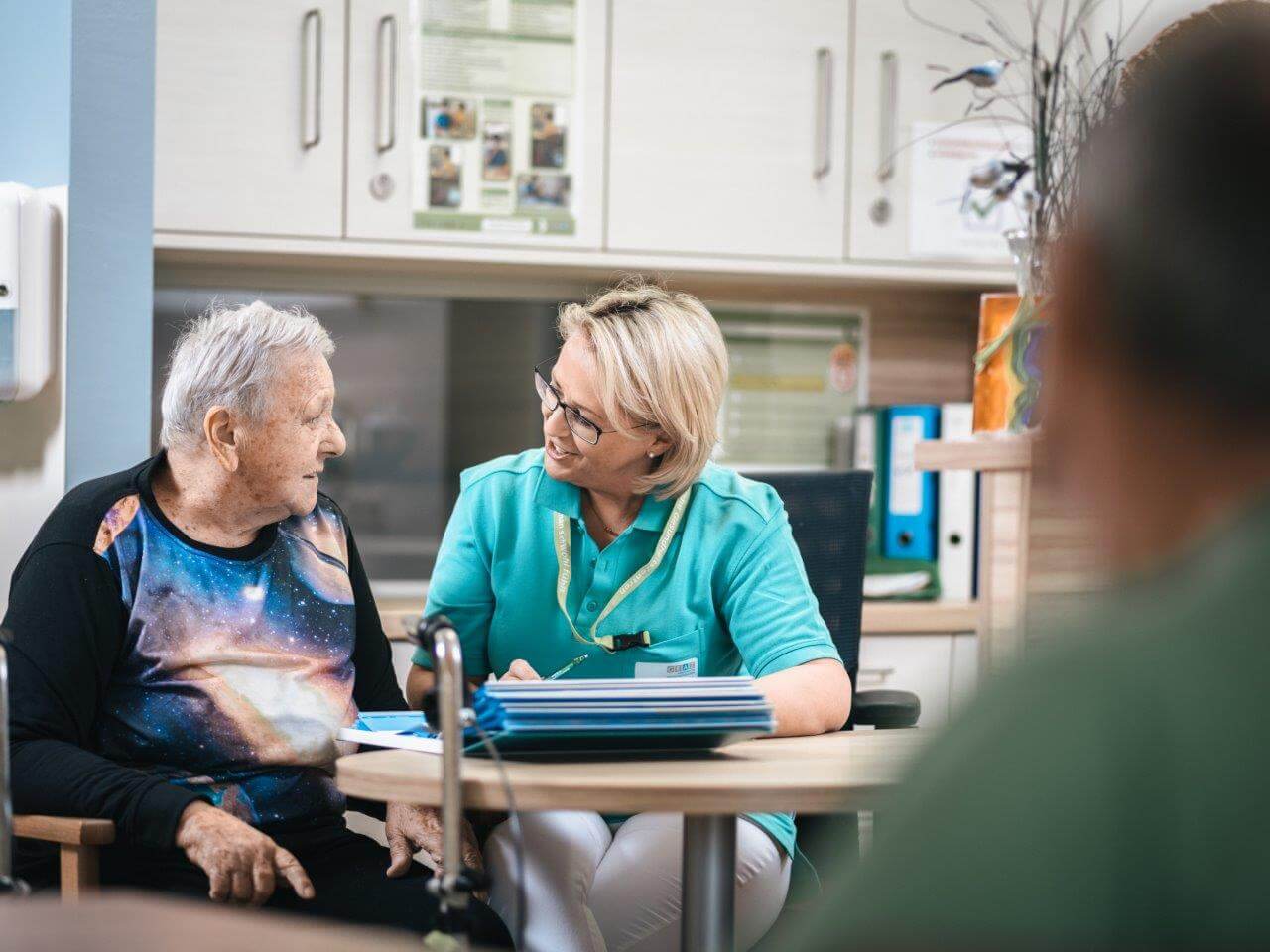 Eine Pflegerin unterhält sich freundlich mit einer älteren Dame.