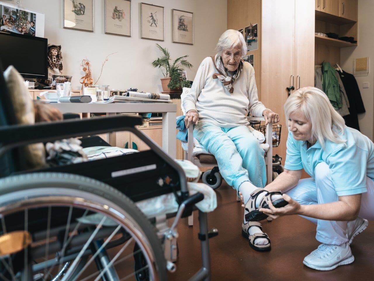 Eine Pflegerin zieht einer älteren Dame die Schuhe an.