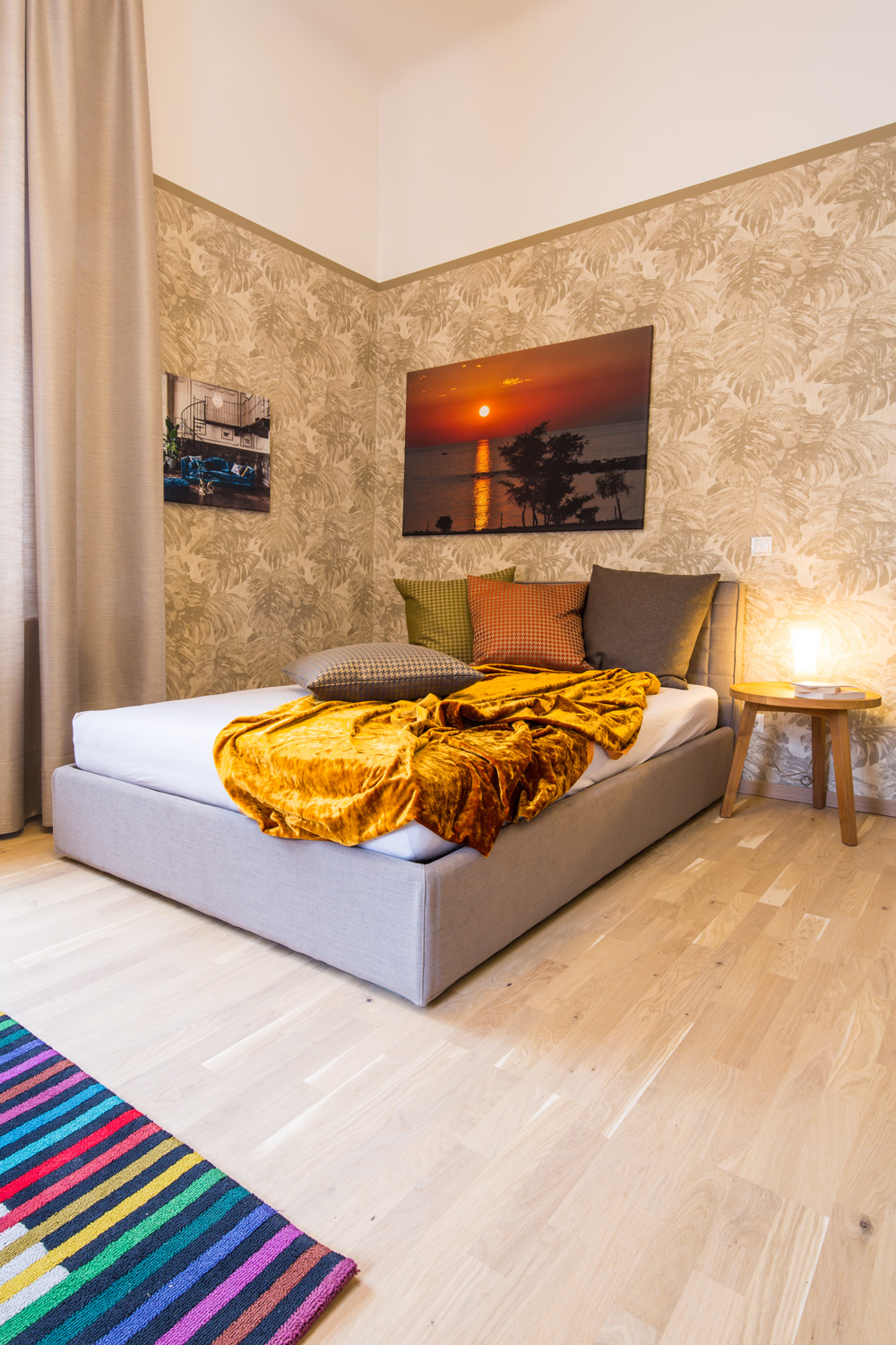 Ein gemütliches Schlafzimmer mit einem großen Bett über dem ein Bild von einem Sonnenuntergang über dem Meer zu sehen ist hängt.