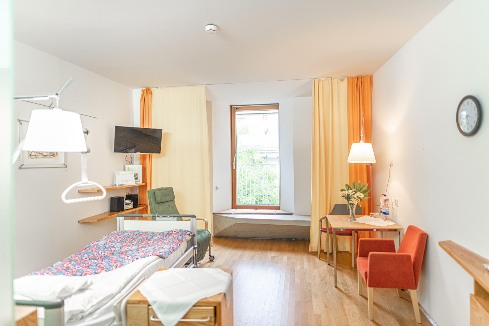 Helles, geräumiges Zimmer mit großem Fenster und Patient:innenbett im Albert Schweitzer Hospiz