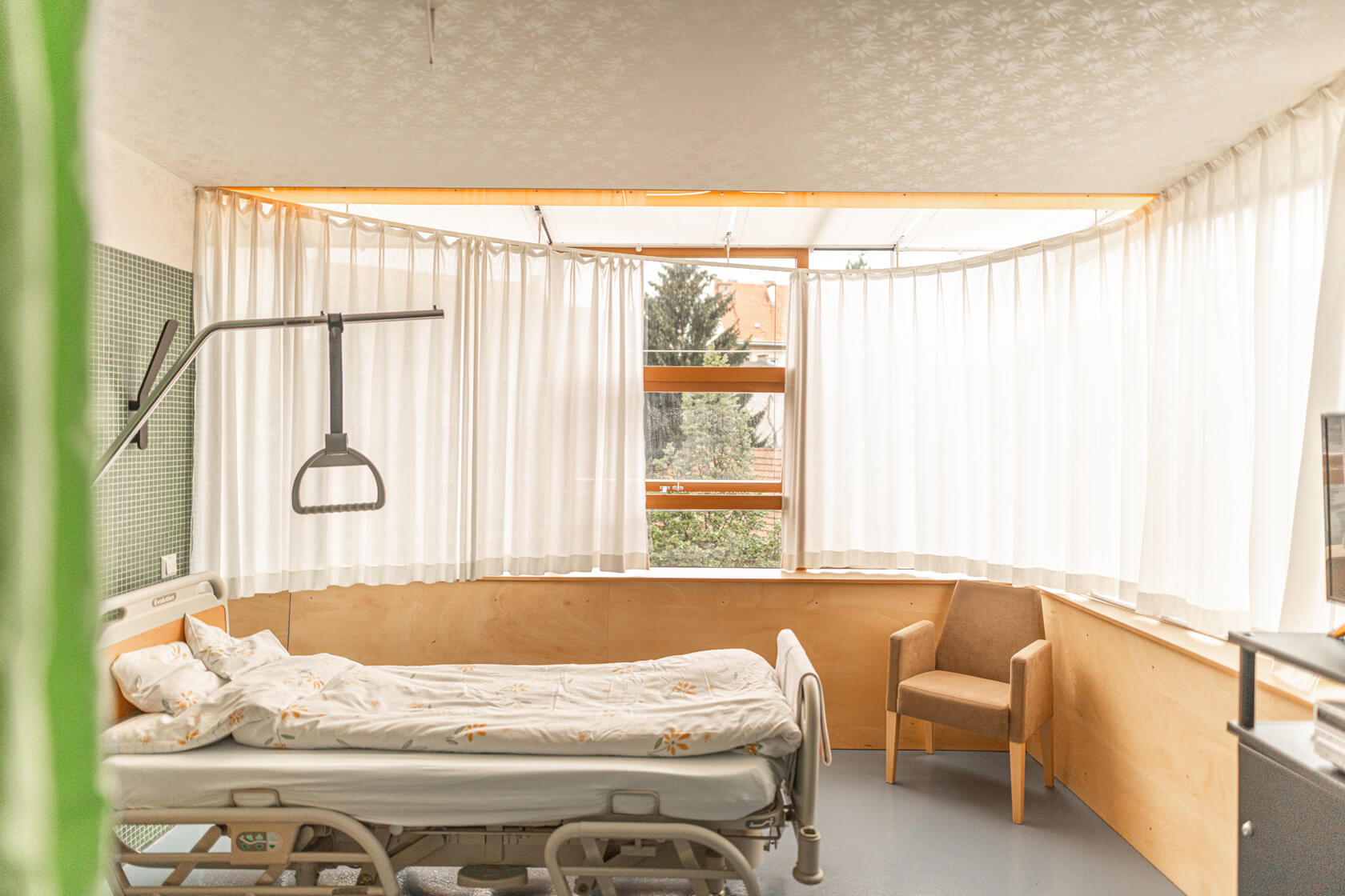 Helles, geräumiges Zimmer mit großem Fenster und Patient:innenbett im Albert Schweitzer Hospiz