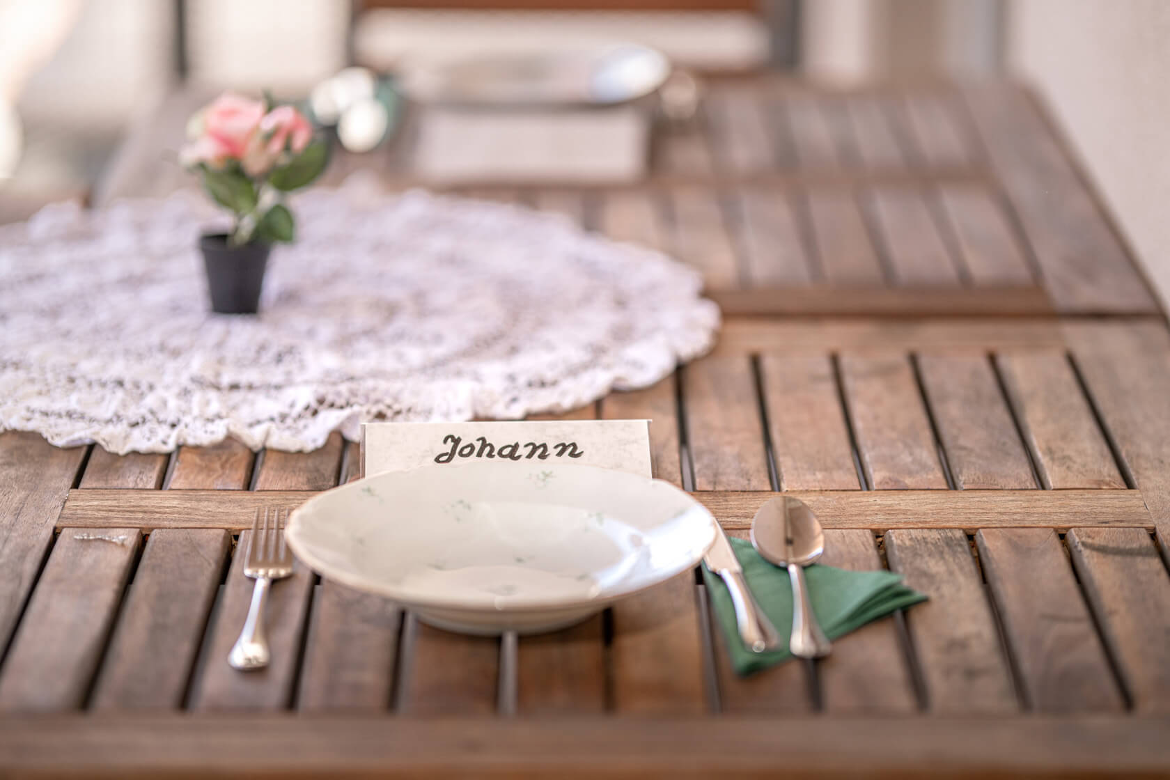 Ein Teller steht auf einem liebevoll dekorierten Holztisch und vor ihm steht ein Namensschild auf dem der Name Johann geschrieben steht.