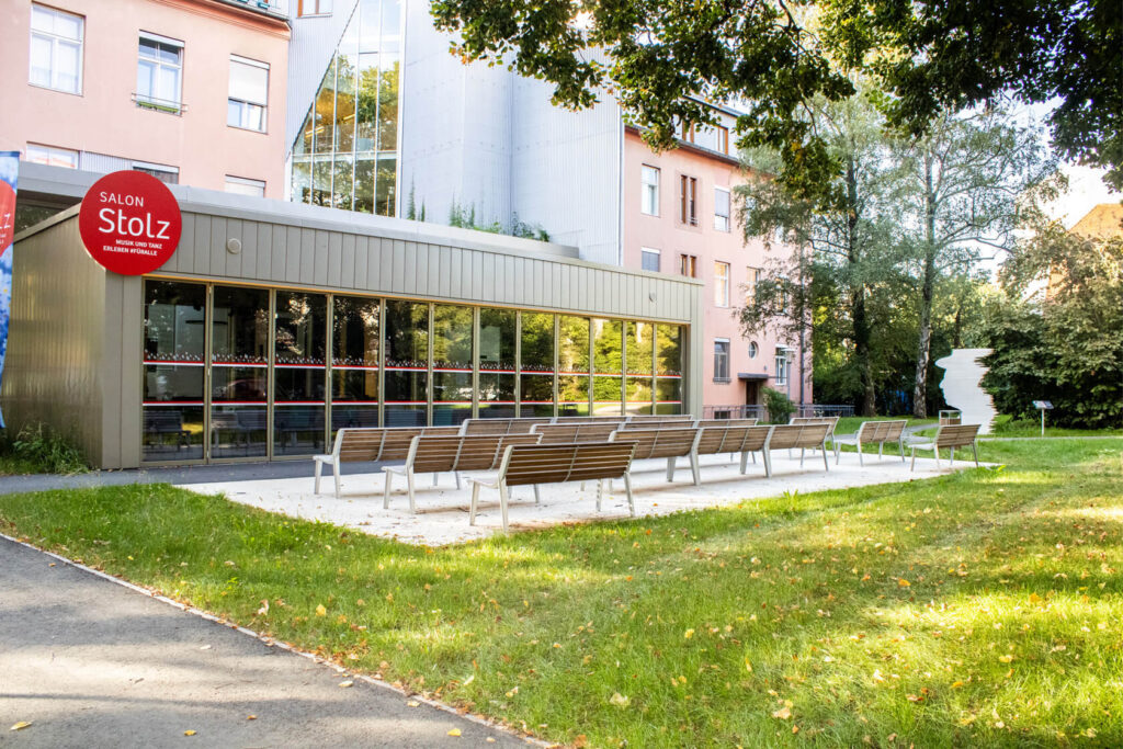 Außenbereich beim Salon Stolz und Senior:innenresidenz Robert Stolz mit Bänken und großer Grünfläche