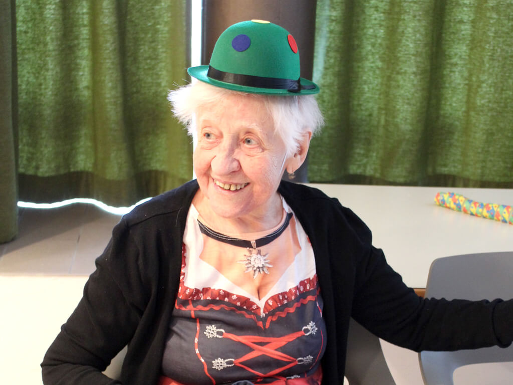 Eine Seniorin verkleidet am Rosenmontag mit Hut und Dirndl.