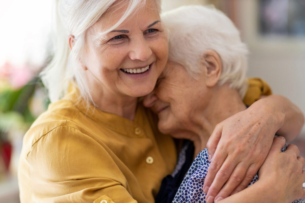 Pflegende Angehörige hält Seniorin im Arm