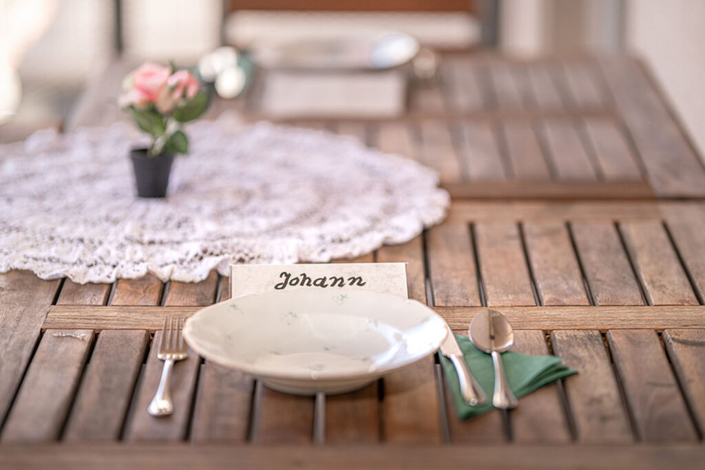 Ein Tisch, auf dem Teller und Besteck liegt und davor ein Namenskärtchen, auf dem Johann steht.