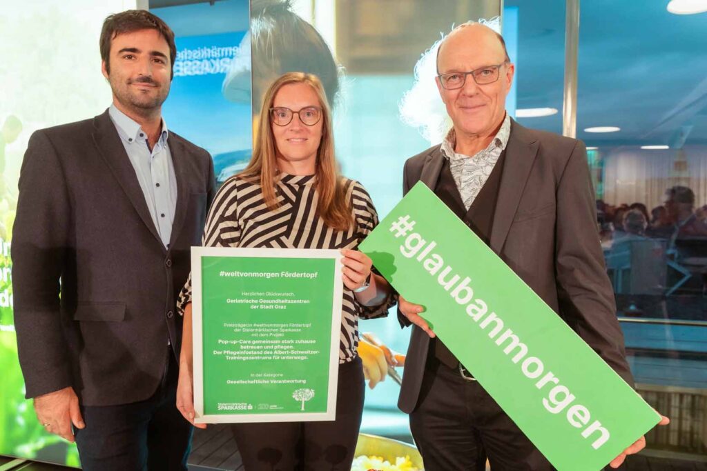 Judith Golbgruber, Gerd Hartinger und Wolfgang Kratky halten die Urkunde und ein Schild von der Auszeichnung #weltvonmorgen