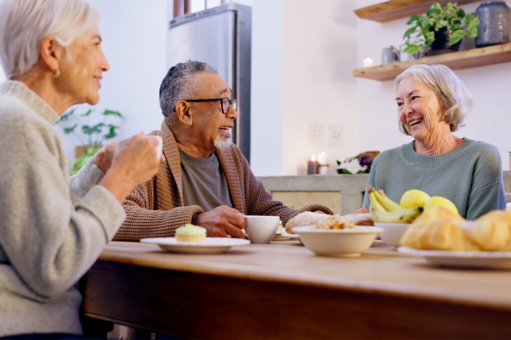 Senior:innen sitzen gemeinsam am Tisch und Frühstücken mit guter Laune
