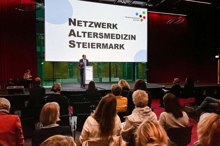 Prim. Walter Schippinger steht auf einer Bühne und begrüßt die Gäste.