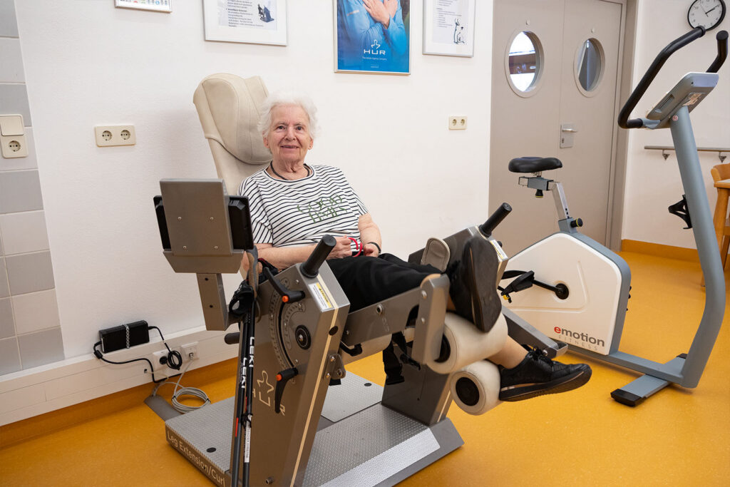 Frau Theuretsbacher sitzt auf einem Übungsgerät des Tageszentrum Robert Stolz